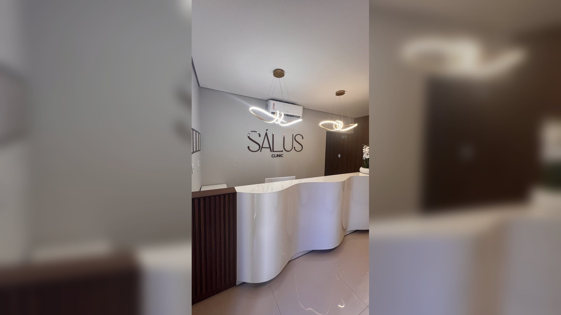 Recep&ccedil;&atilde;o da S&aacute;lus Clinic com logo e decora&ccedil;&atilde;o de orqu&iacute;deas